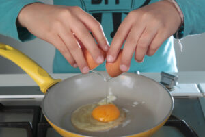 Foto: Ein Ei wird in eine Pfanne gegeben